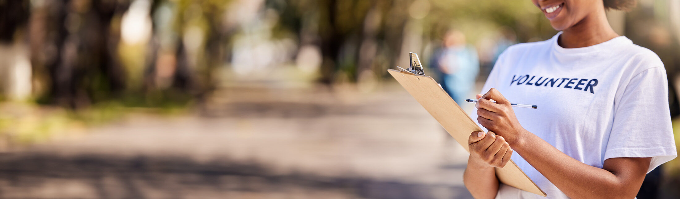 A woman in a white shirt holds a clipboard, appearing focused and engaged in her task.