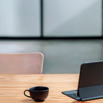 A laptop on a table beside a steaming cup of coffee, creating a cozy workspace atmosphere.