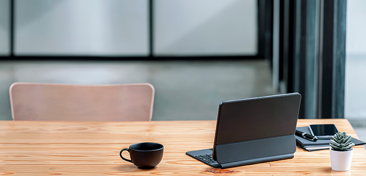 A computer and a cup of freshly brewed coffee share table space, evoking a comfortable home office vibe.